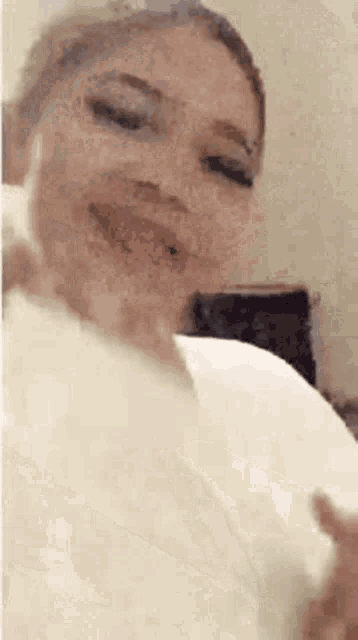 a woman is sitting on a bed with her eyes closed and a white towel around her neck .