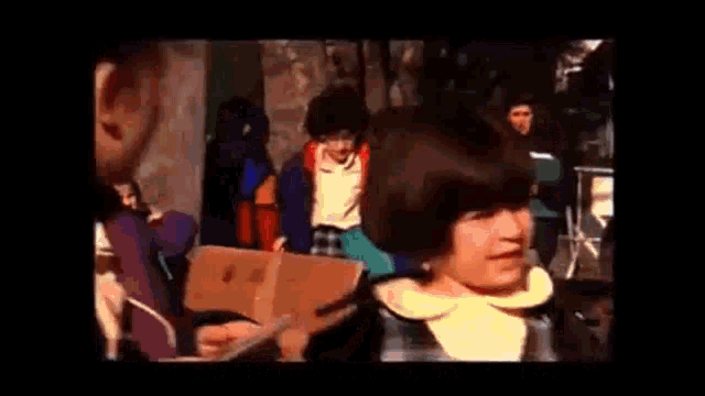 a group of people are walking down a street with a sign that says `` the purpose of them coming to school ''
