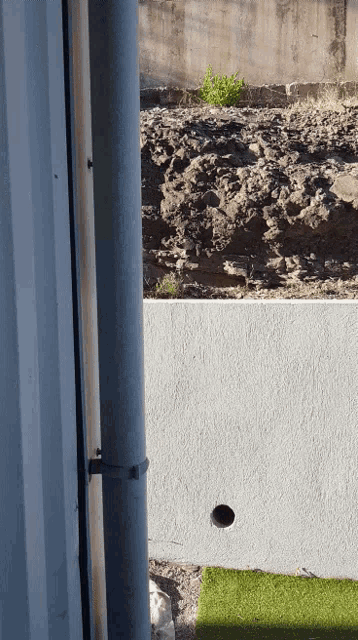 a hole in a wall with a drain pipe in the foreground