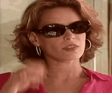 a woman wearing sunglasses and hoop earrings is giving a thumbs up .