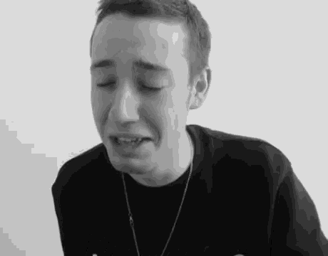 a black and white photo of a young man crying with his eyes closed .