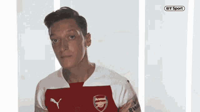 a man in a red and white arsenal jersey is looking at the camera .