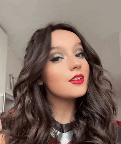 a close up of a woman 's face with long hair and red lipstick