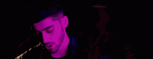 two men are standing next to each other in a dark room in a purple light .
