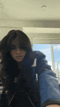 a woman is taking a selfie in front of a window .