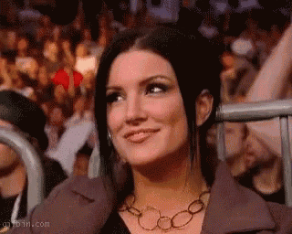a woman is smiling while sitting in a crowd of people at a concert .