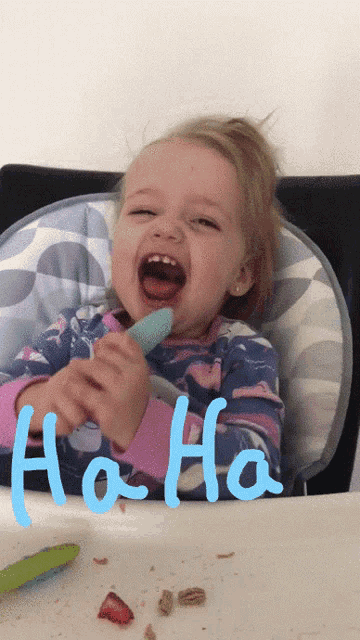 a little girl in a high chair is laughing with the word ho-ho written in blue