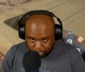 a man wearing headphones is sitting in front of a microphone and making a funny face .