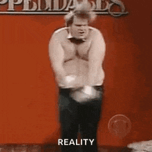 a shirtless man is dancing on a stage in front of a sign that says reality .