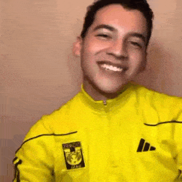 a man wearing a yellow adidas jacket is smiling .