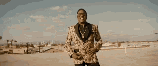 a man in a suit is talking on a cell phone while standing on a rooftop .