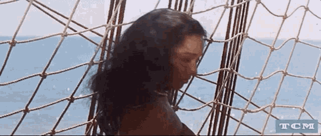 a woman is behind a rope fence with tcm written in the corner