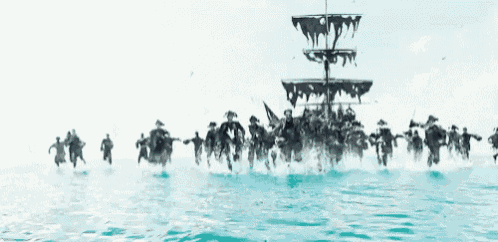 a group of people are running in the water in front of a large ship .