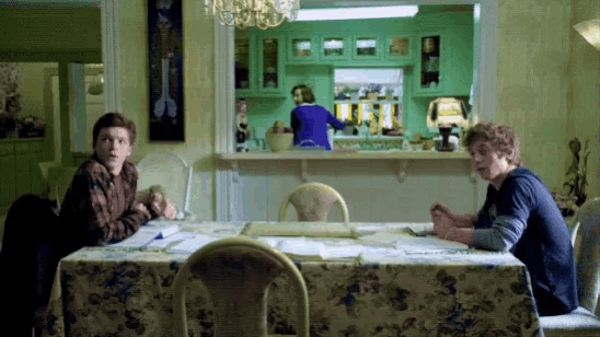 two men sit at a table in a dining room