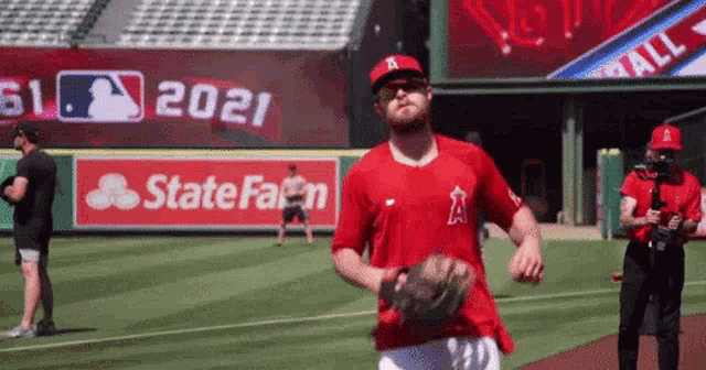 a man in a red shirt with the letter a on it is running on a baseball field .