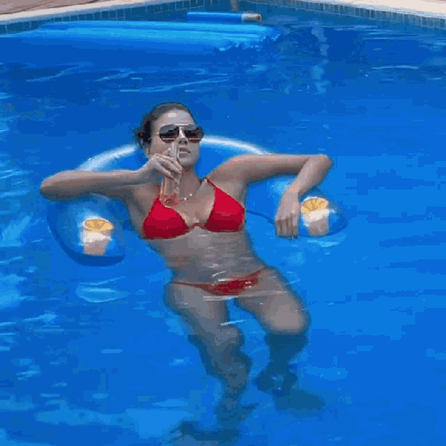 a woman in a red bikini is floating on a blue raft in a pool