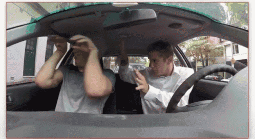 two men are sitting in a car with their hands in their hair
