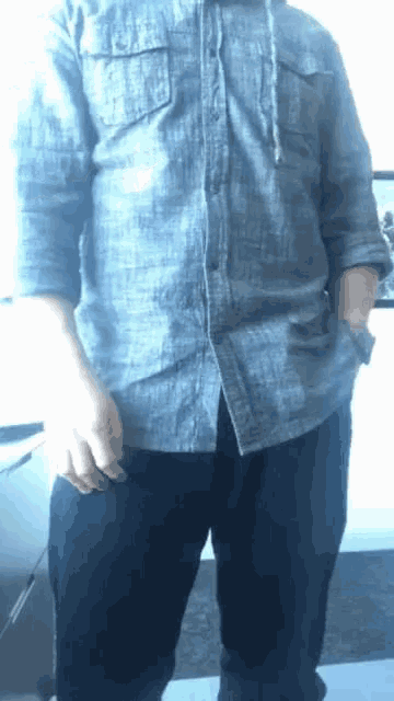 a man with his hands in his pockets wearing a blue shirt