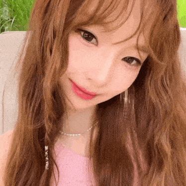 a close up of a woman 's face wearing a pink top