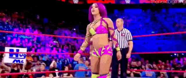 a female wrestler is standing in a wrestling ring with a referee .