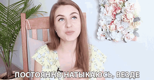 a woman is sitting in a chair in front of a wall with flowers and the words " постоянно " written on it