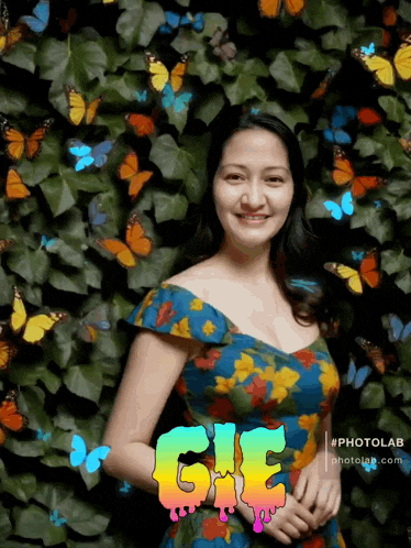 a woman in a floral dress stands in front of a wall of butterflies with the word gif written on the bottom