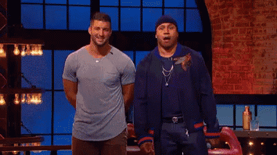 two men are standing next to each other on a stage with a brick wall behind them .