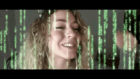 a woman with curly hair is smiling in front of a matrix screen