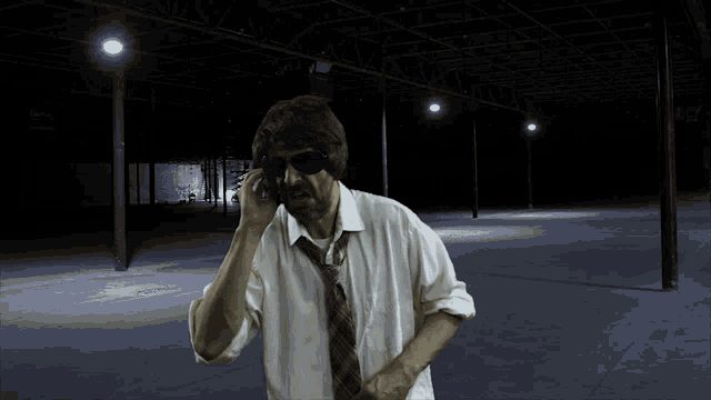 a man wearing sunglasses and a tie talks on a cell phone