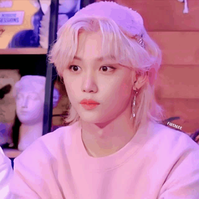 a young man with blonde hair is wearing a pink sweater and a pink hat .