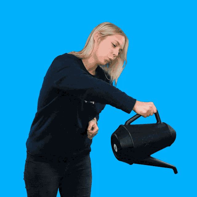 a woman holding a black watering can with the word spooky on her shirt