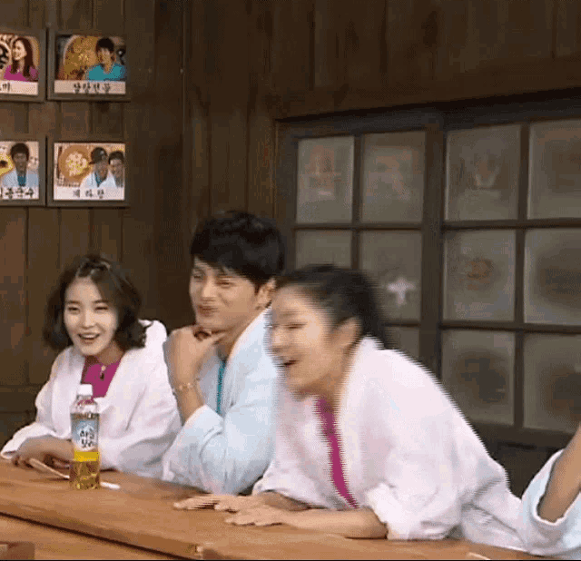 a group of people are sitting at a table with a bottle of fanta on it