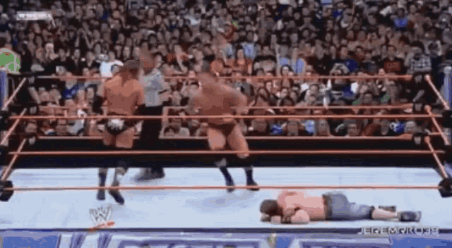 a wrestler is laying on the ground in a wrestling ring in front of a crowd