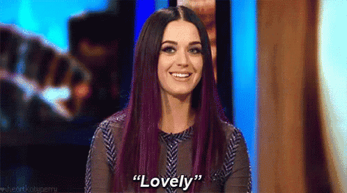 a woman with purple hair is smiling and saying `` lovely '' on a television show .