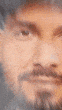 a close up of a man 's face with a beard and a hat