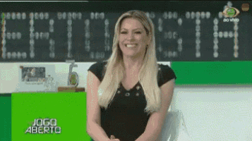 a woman in a black shirt is smiling in front of a scoreboard that says jogo aberto