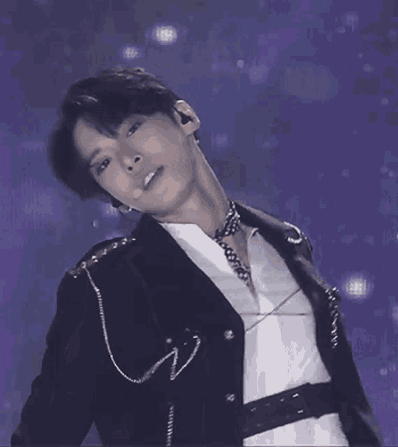 a young man wearing a black jacket and a white shirt is dancing on a stage