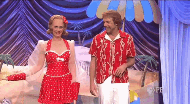 a woman in a red polka dot dress stands next to a man in a red and white striped shirt