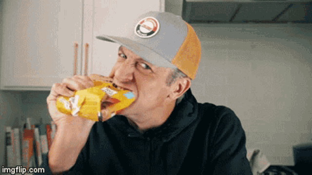 a man wearing a hat is eating a bag of lays chips