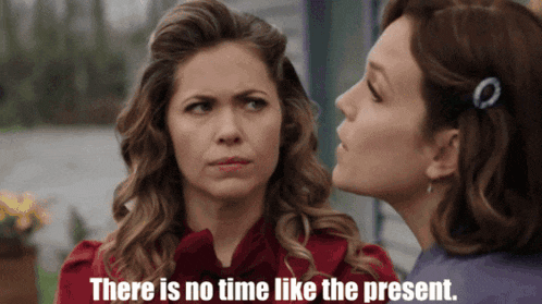a woman whispering into another woman 's ear with the words there is no time like the present