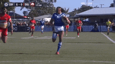 a group of rugby players are running on a field with the ball .