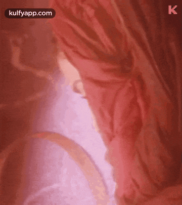 a close up of a person 's face behind a red curtain