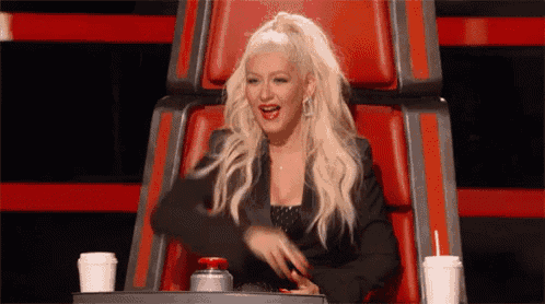 a woman is sitting in a chair with two cups of coffee and a button .