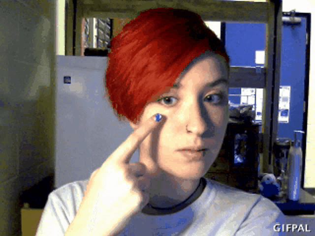 a woman with red hair is pointing at her eye with a gifpal watermark