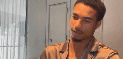 a man with a beard is sitting at a table in a room .