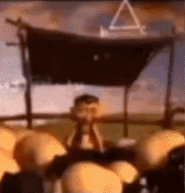 a blurry picture of a cartoon character sitting in front of a pyramid .