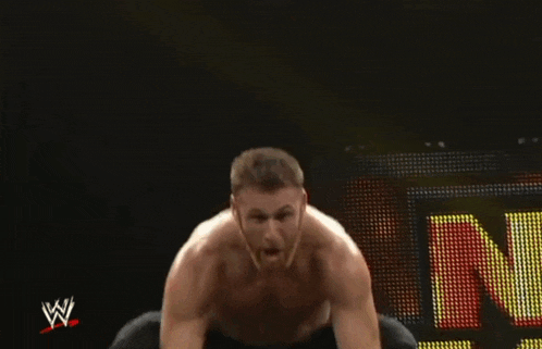 a wrestler sitting in front of a sign that says n.