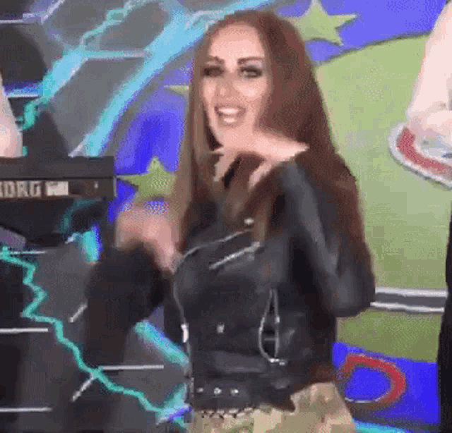 a woman in a black leather jacket is standing in front of a korg keyboard