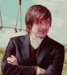 a man with his arms crossed is wearing a suit