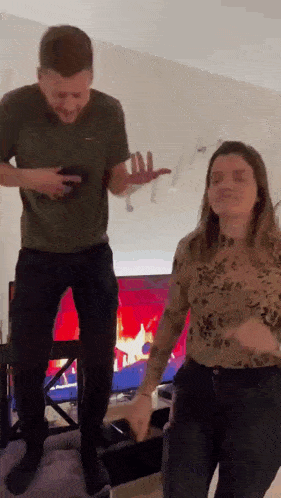 a man and woman are dancing in front of a tv